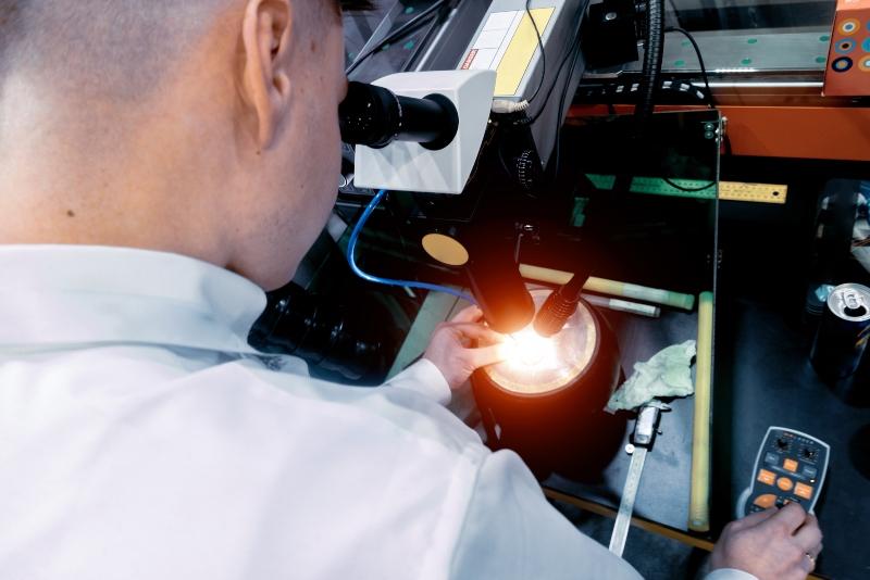Mann schweisst mit einem Laser und einem Mikroskop ultrapraezise Kleinteile