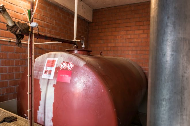 Alter, roter Heizöltank steht im klassisch gemauerten Kellerraum